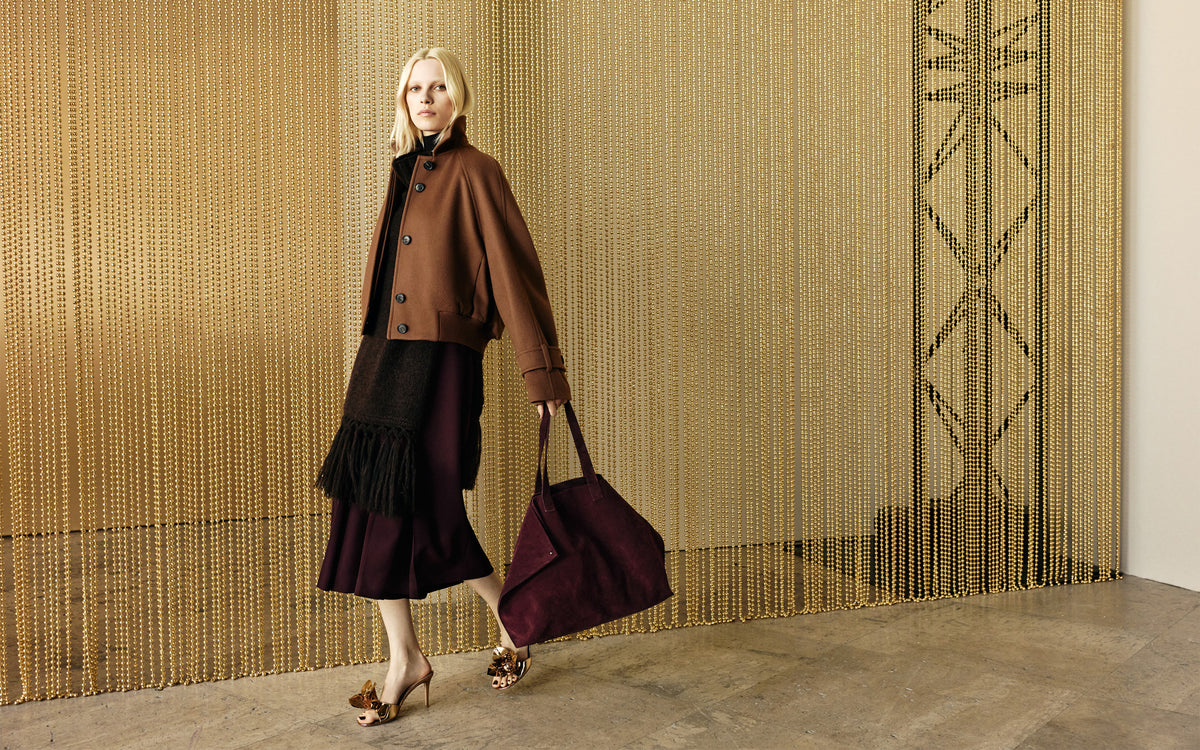 Look from the Akris Fall 2026 collection featuring elevated knitwear, refined outerwear, and the iconic Ai handbag in seasonal burgundy tones.