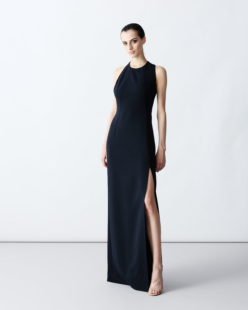 Elegant black sleeveless maxi dress with a high neckline and a deep side slit. The look is completed with snake-print ankle boots for a modern luxury aesthetic.