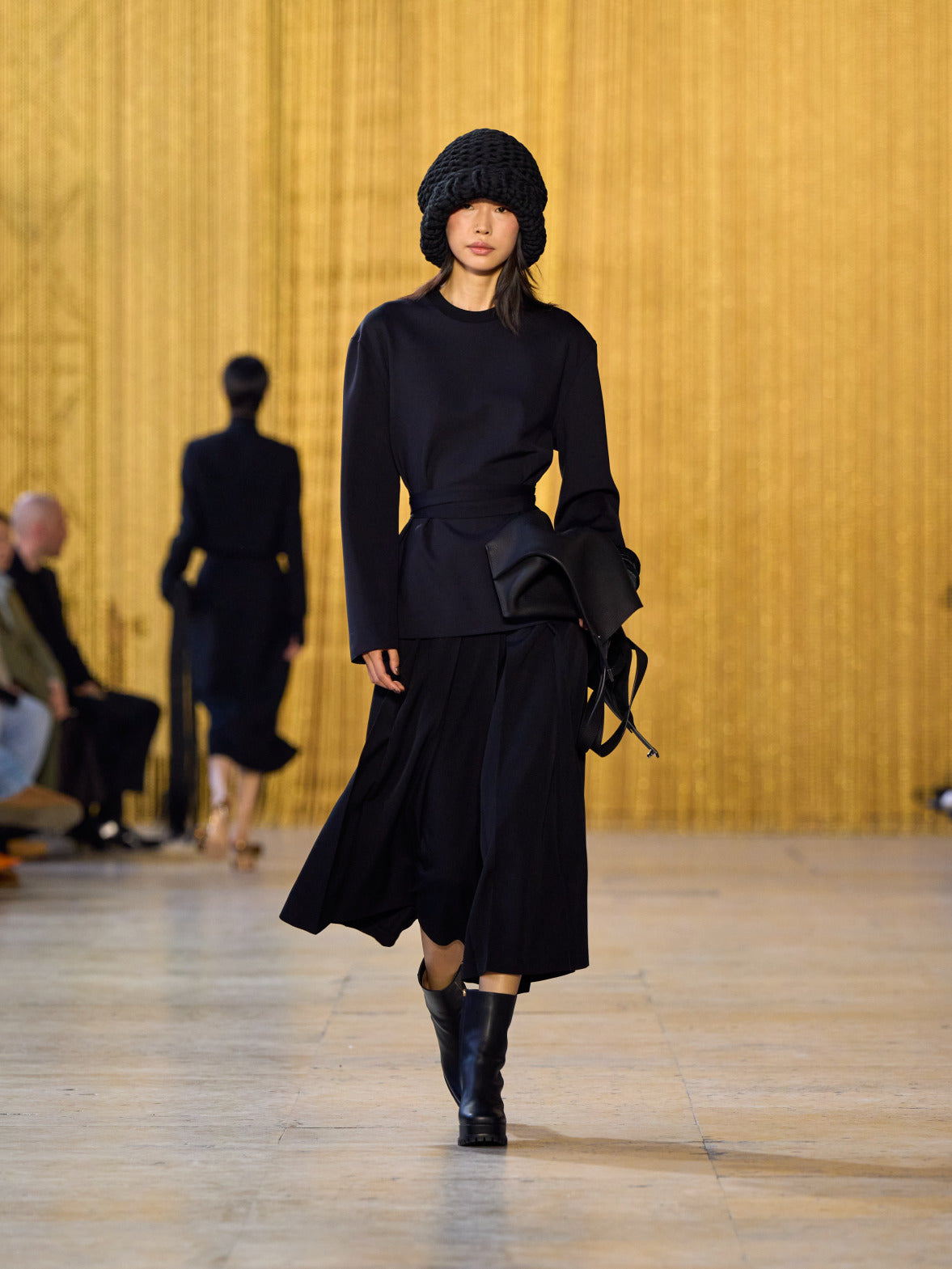 A tribute to Olga de Amaral in the Akris FW26 collection in Paris, defined by a dialogue between deep blacks, burgundy, and metallic gold accents