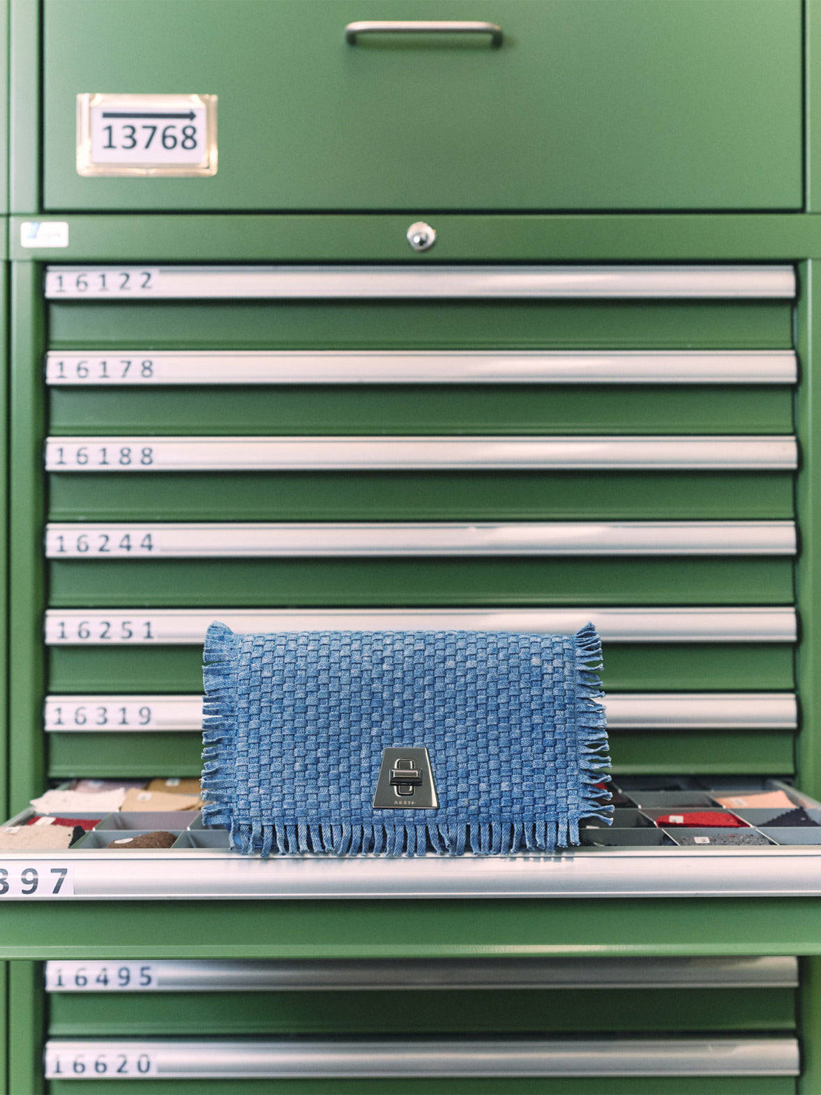 Designer braided denim handbag from the Cruise 2026 collection, showcasing intricate textile craftsmanship in a studio setting.