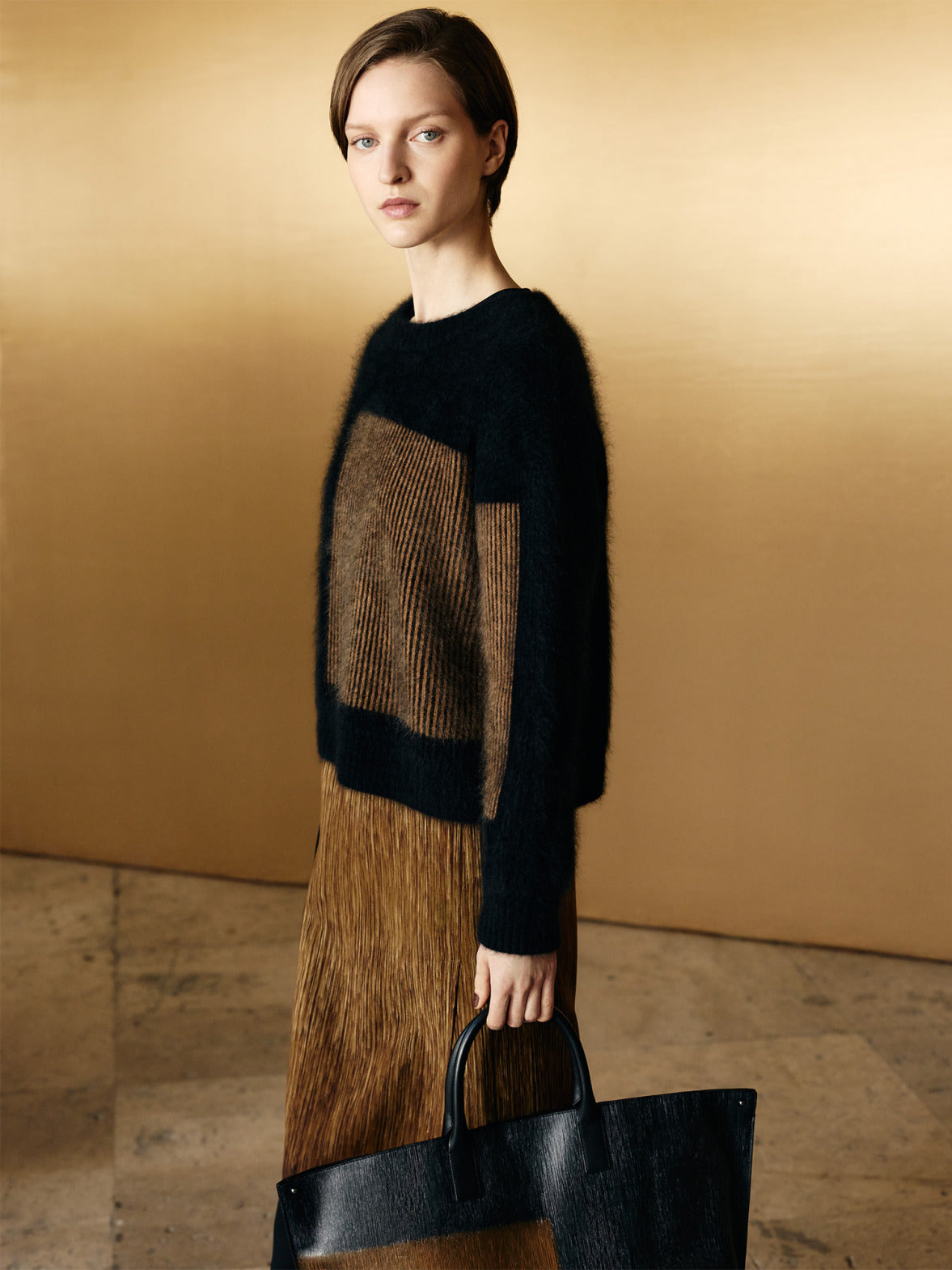 Akris Fall 2026 knitwear featuring a Cloud Cashmere sweater with the gold-toned Oro Lienzo print inspired by artist Olga de Amaral and a dress and bag with the same print.