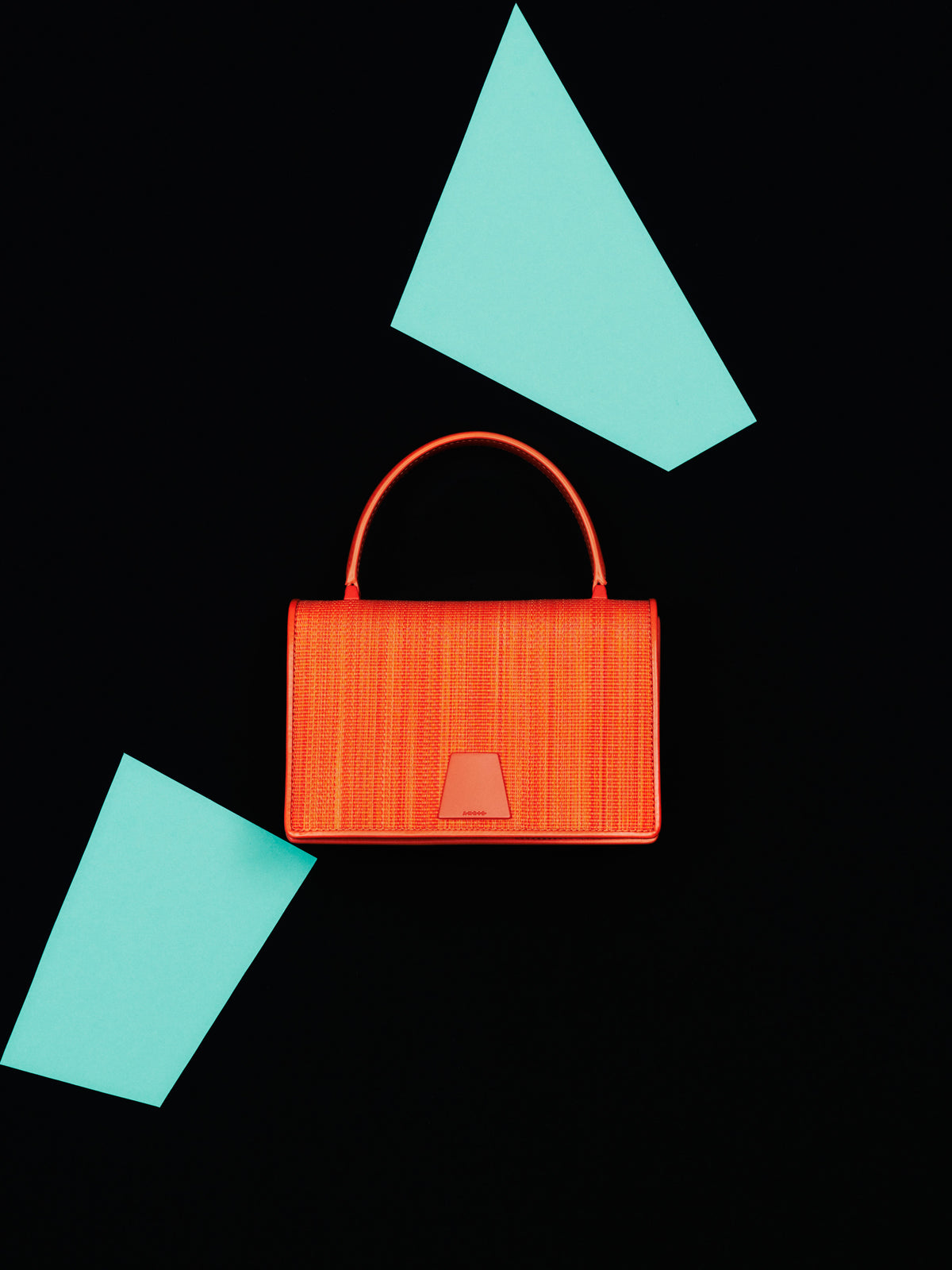 Discover the textured elegance of the Akris Pre-Fall collection, showcasing the sophisticated Alice handbag crafted in premium horsehair. Artfully presented against a minimalist black backdrop with striking red geometric accents, this luxury piece defines modern artistic refinement. Experience exceptional Swiss craftsmanship and unique materials.