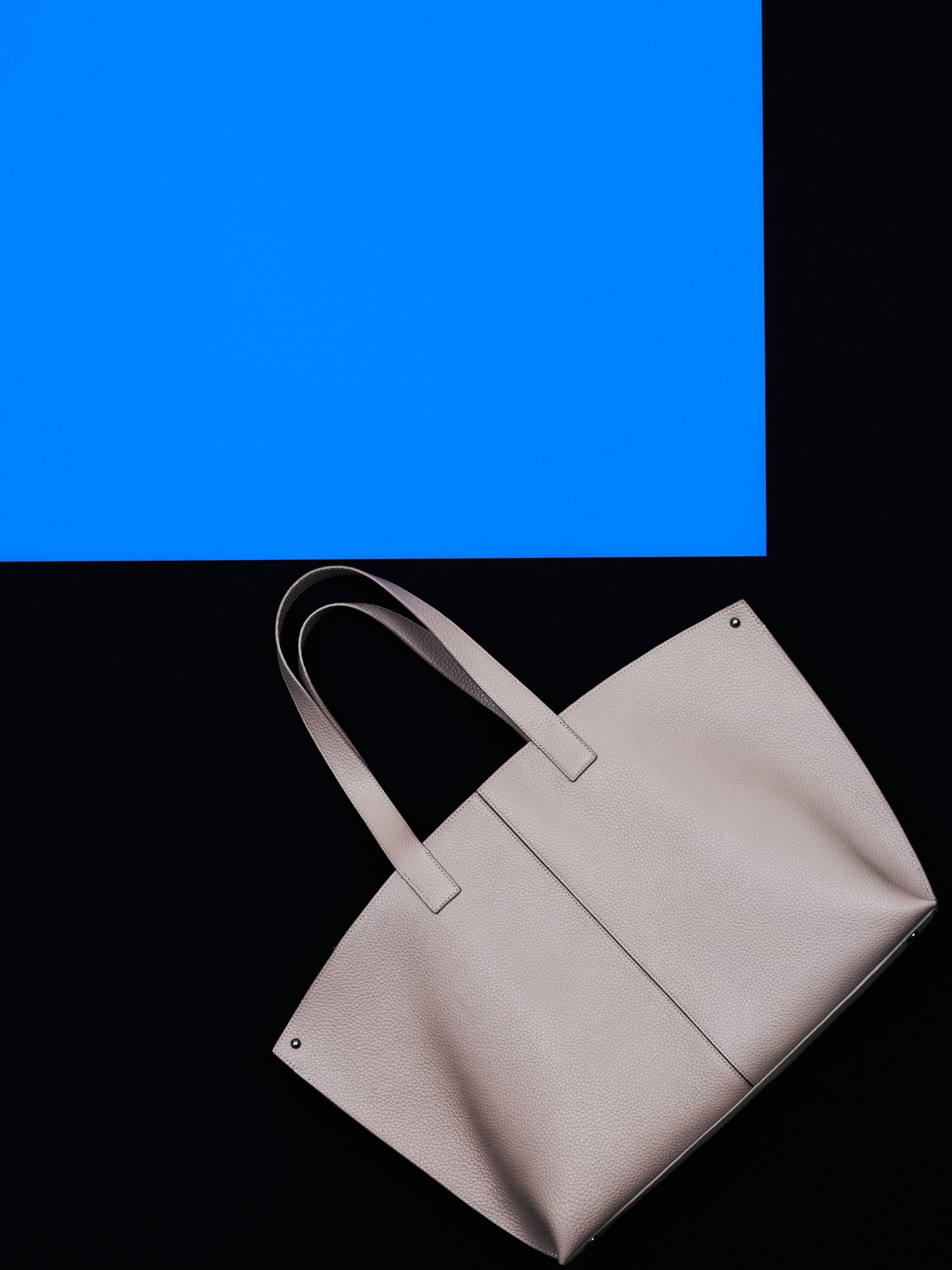 Discover the effortless charm of the Akris Pre-Fall collection, showcasing a classic white button-down shirt paired with an elegant beige pleated skirt. The look is beautifully complemented by a slouchy, cream-colored luxury shoulder bag. Elevate your everyday style with refined minimalism and premium Swiss design.