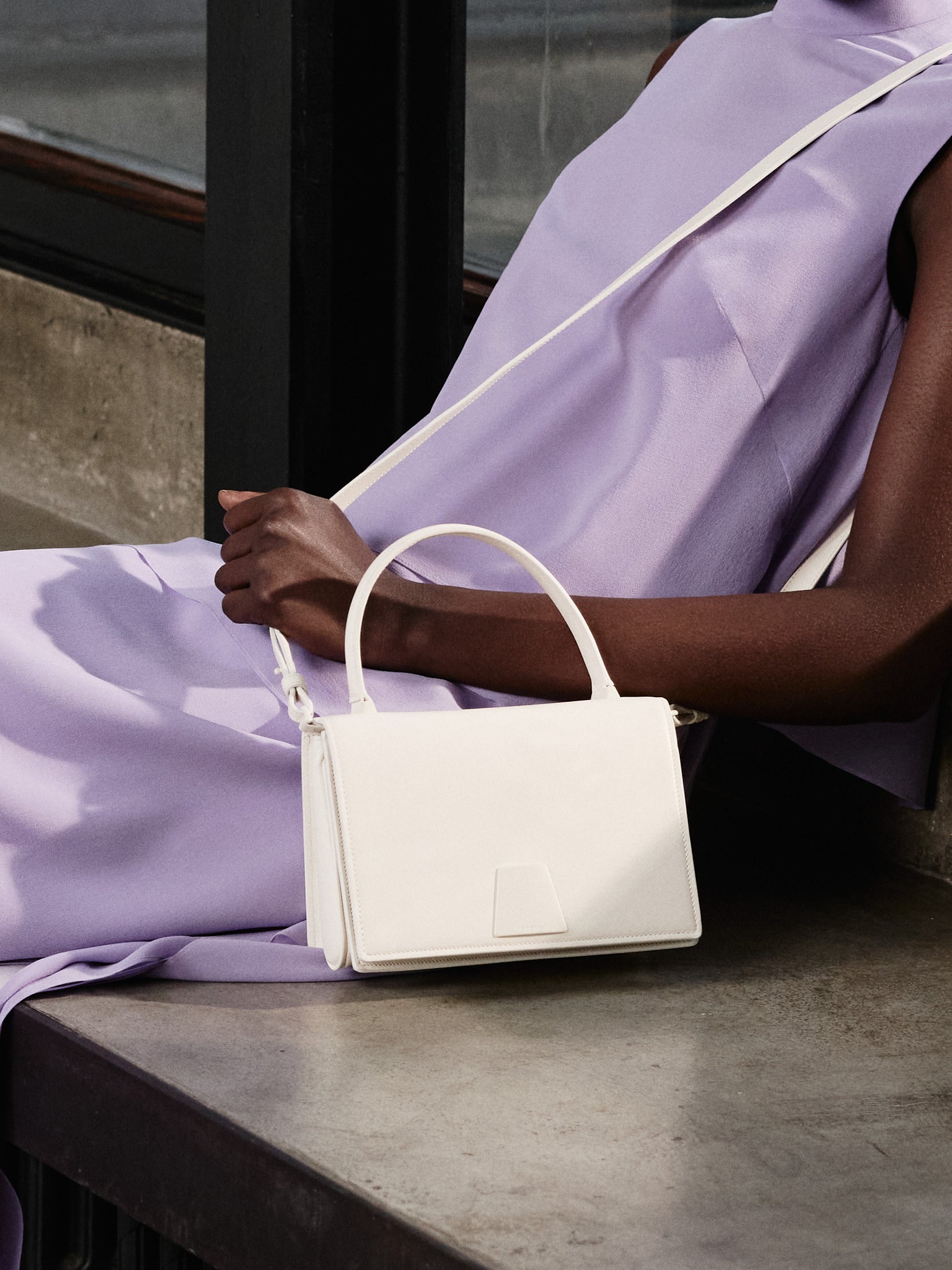 Embrace effortless refinement with the Akris Pre-Fall collection, featuring a stunning monochromatic look in a delicate wisteria violet shade. Complete the elegant draped ensemble with the minimalist chic of the white Alice handbag. Discover the perfect balance of fluid tailoring and timeless luxury craftsmanship.