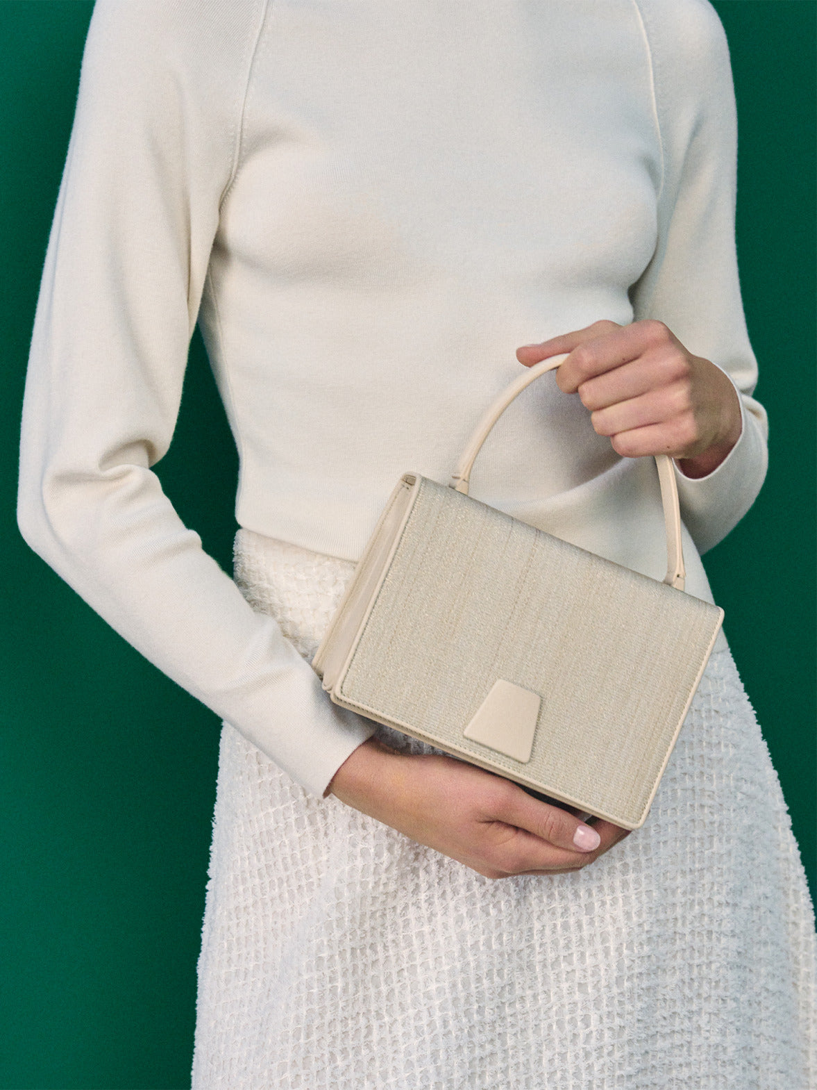 Akris Spring/Summer trapezoid handbag in textured beige fabric. A close-up highlighting the refined woven material, minimalist handle, and signature architectural clasp.